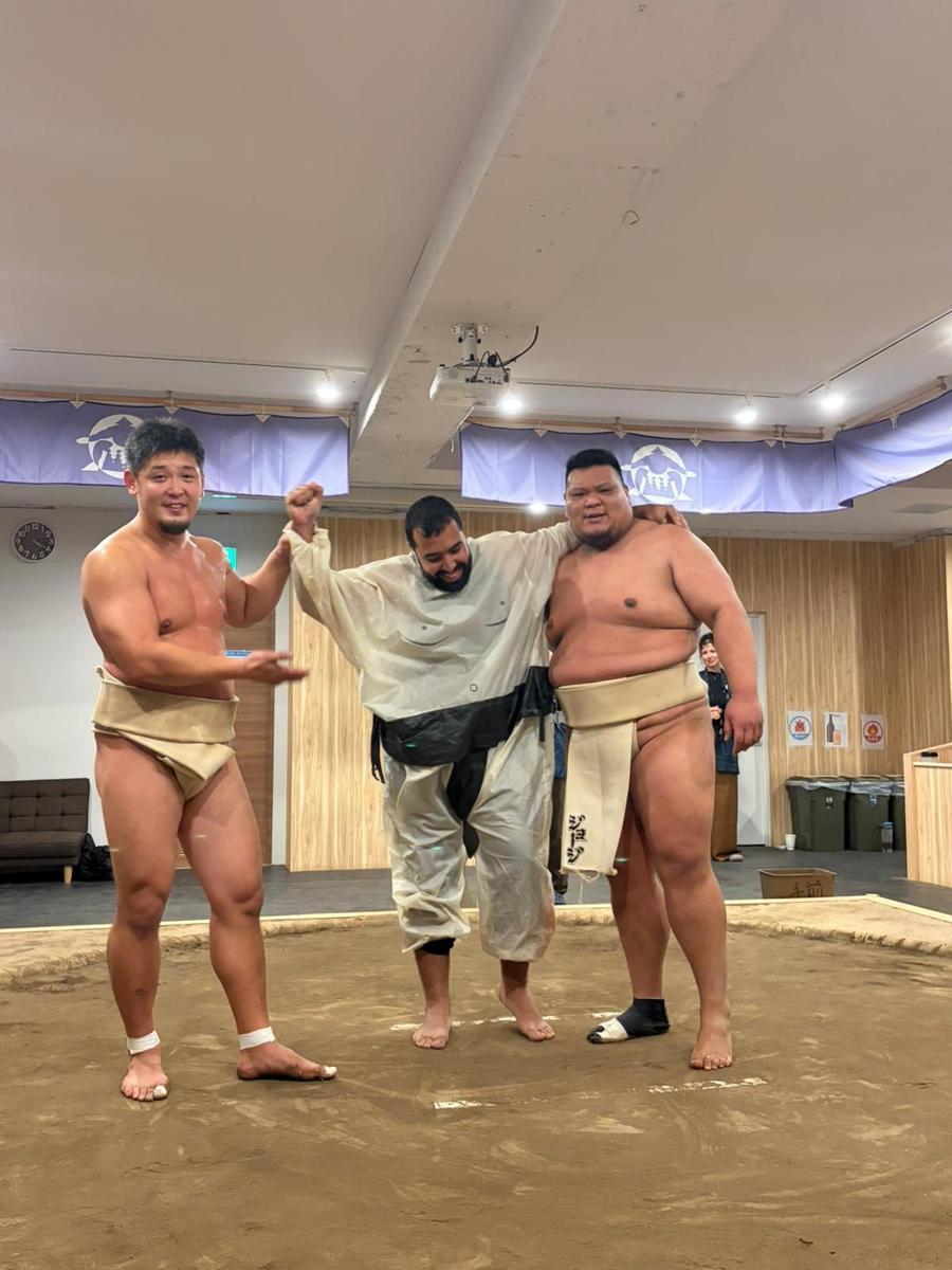 Younes sur le dohyo avec deux lutteurs de sumo à Tokyo, Japon